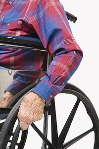 Caucasion male elderly hands gripping wheels of wheelchair.