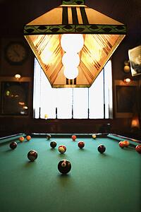 Green billiards table with pool balls spread out.
