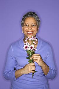 African American mature adult female holding flowers.