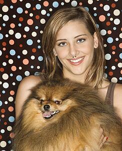 Caucasian teen female holding Pomeranian dog.