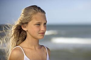 Portrait of pre-teen girl on beach with ocean waves in background. 