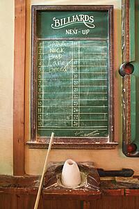 Chalkboard queue for people waiting to play billiards in nightclub with chalk and pool stick.
