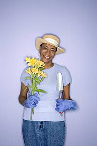 African American mature adult female with hand shovel and flowers.