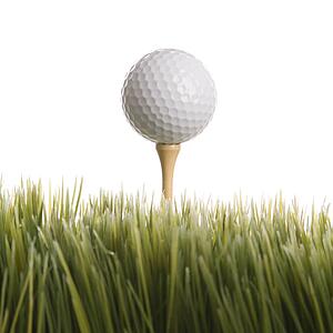 Studio shot of golf ball resting on tee in grass.