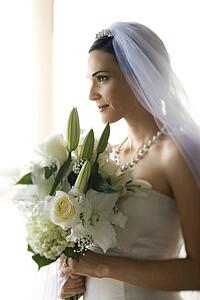 Profile portrait of Caucasian mid-adult bride holding flower bouquet.