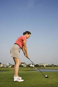 Caucasion mid-adult woman preparing to drive golf ball.