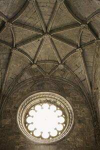 Rib-vaulted ceiling and sunlit window in Jeronimos Monastery in Lisbon, Portugal.