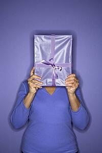 African American mature adult female holding present in front of face.