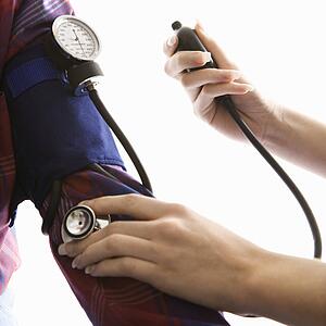 Close-up of mid-adult Caucasian female taking blood pressure of a male.