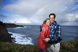 Caucasian couple embracing with rainbow in background in Maui Hawaii