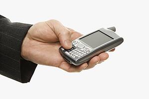 Close-up of Caucasian middle-aged businessman using handheld PDA.