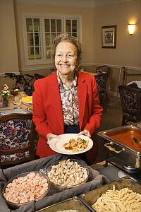 Elderly Caucasian woman at buffet in the dining room of a retirement community center.
