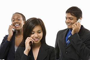 Multi-ethnic businesswomen and businessman standing talking on cell phones.