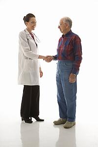 Mid-adult Caucasian female doctor shaking hands with an elderly Caucasian male.
