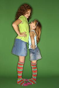 Caucasian female children standing face to face looking at each other.