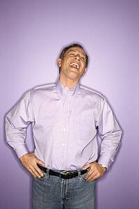 Laughing middle-aged Caucasian man wearing purple clothing on purple background.