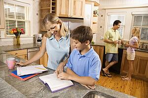 Caucasian family in kitchen doing homework and chatting.