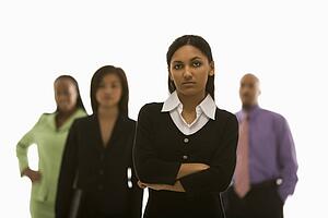 Portrait of Indian businesswoman with arms crossed with others in background.