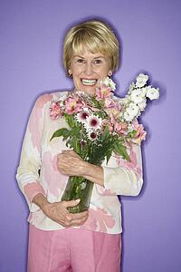 Caucasian mature adult female holding flower bouquet.