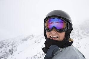 Caucasian teenage boy skier in helmet and goggles at ski resort on mountain.