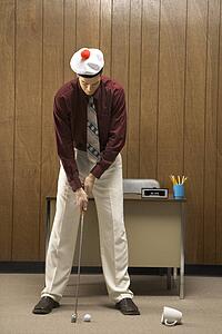 Caucasion mid-adult retro businessman wearing cap putting golf ball into coffee cup in his office.