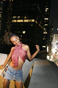 Young sexy African-American woman jumping and screaming with excitement on patio in New York City, New York at night.
