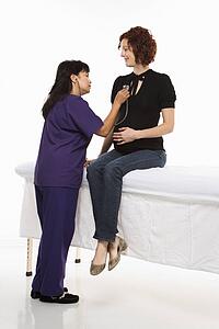 Pregnant Caucasian mid-adult woman having vital signs checked by nurse.