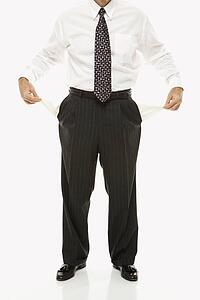 Caucasian middle-aged businessman pulling empty pockets out standing against white background.