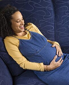 Portrait of young pregnant female with hands on stomach.