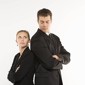 Caucasian mid-adult businessman and woman standing back to back looking at each other. 