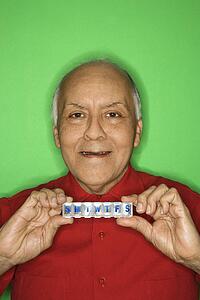 Mature adult Caucasian male holding pill organizer.