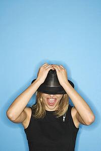 Caucasian young adult female pulling hat down over eyes.