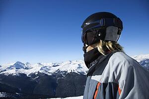 Caucasian teenage boy snowboarder wearing helmet and goggles on mountain.