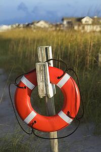 Life preserver hanging on post on beach.