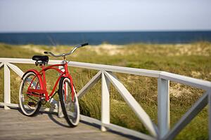 Red beach cruiser bicycle leaning against walkway rail on beach on Bald Head Island, North Carolina.