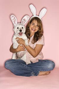 Caucasian prime adult female and white terrier dog wearing rabbit ears.