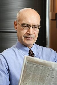 Caucasian middle-aged businessman sitting in office reading newspaper.