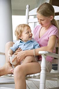 Pre-teen girl holding a toddler looking at each other