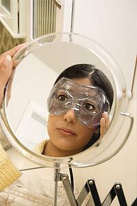 Close up mirror reflection of Asian/Indian young woman wearing eye mask.