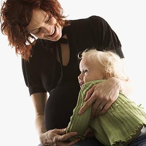 Pregnant Caucasian mid-adult woman hugging her daughter.