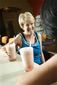Mature Caucasian adult females sitting at table in health club cafeteria.