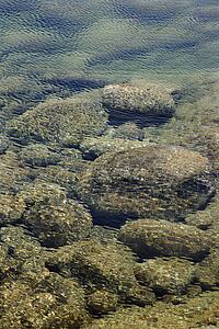 Rocks on ocean bottom seen through clear, rippled water in Maui, Hawaii, USA.