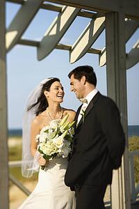 Caucasian mid-adult bride and groom looking at each other talking and laughing.