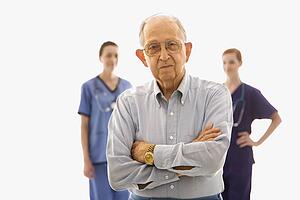 Elderly Caucasian male in foreground with two Caucasian females in the background.
