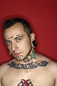 Caucasian mid-adult man with tattoos and piercings.