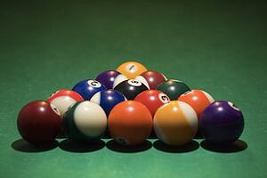 Rack of pool balls on green billiards table.