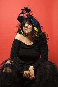Portrait of Caucasian woman in unique makeup and clothing against red background.