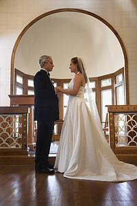 Protrait of bride and groom holding hands at the alter of a church.