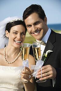 Caucasian mid-adult bride and groom toasting champagne looking at viewer and smiling.