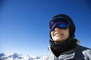 Caucasian teenage boy snowboarder wearing helmet and goggles on mountain.